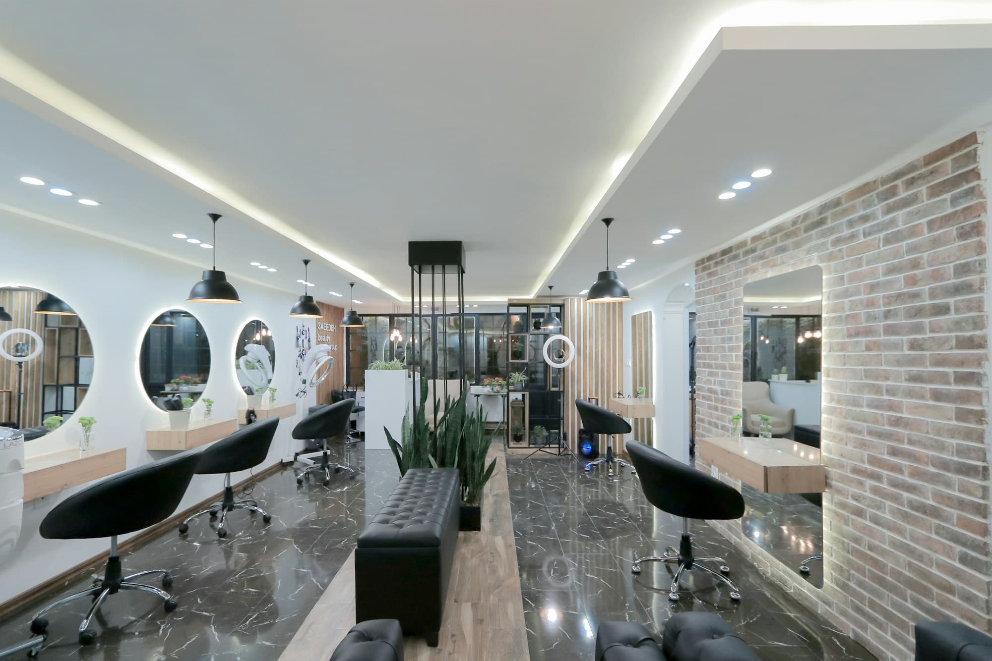 Bright salon with black styling chairs, round mirrors and a brick wall