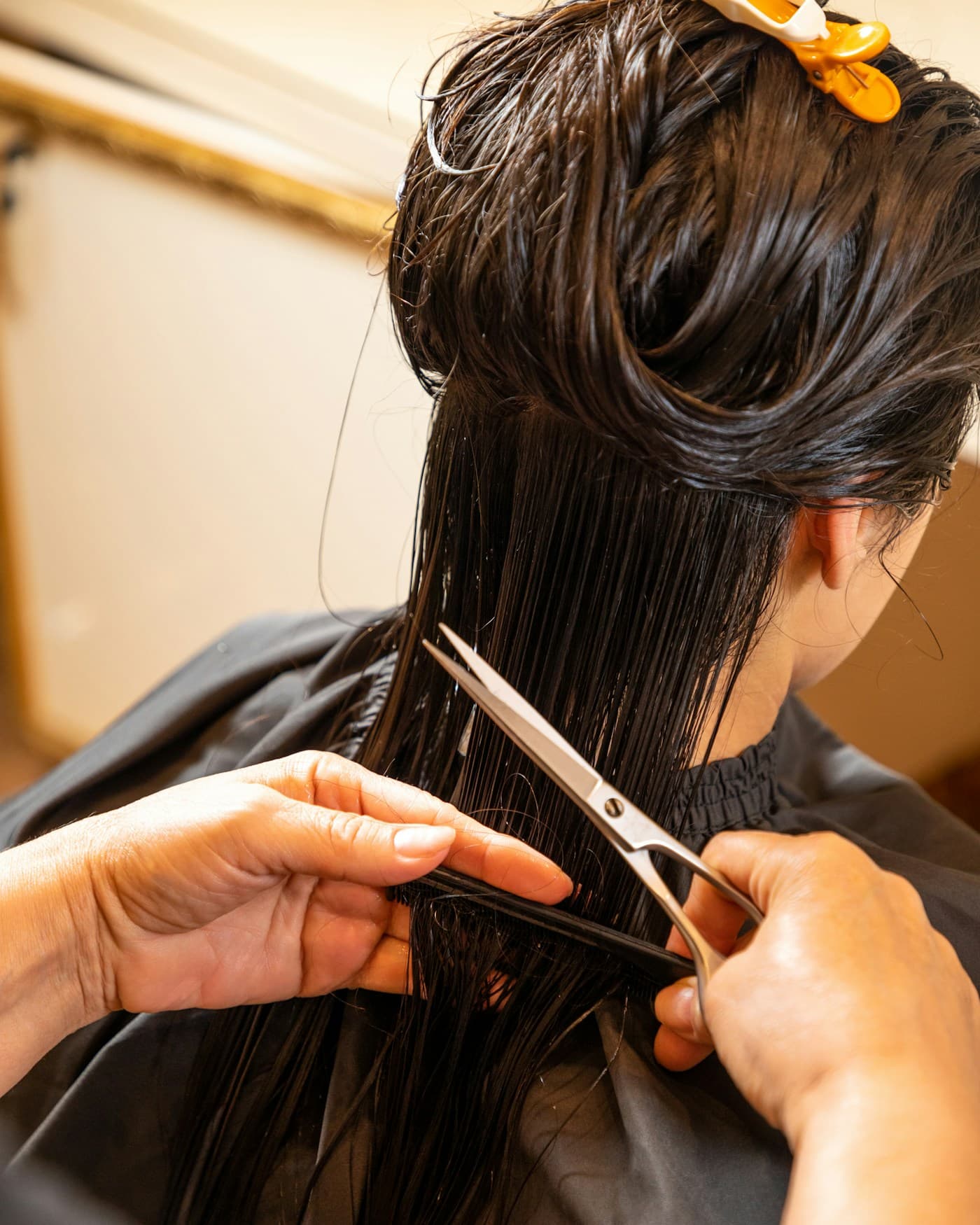 Stylist cutting a client's dark hair with scissors